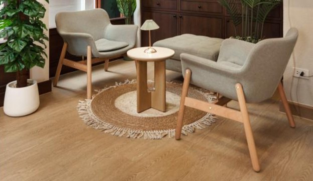 The lounge: armchairs and a low table on a jute rug, framed by a monstera and a palm